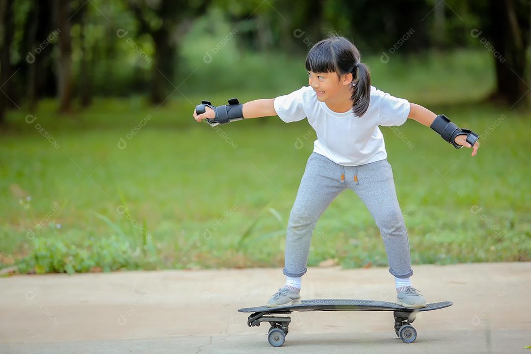Menina bonitinha asiática andando de skate no parque de skate.