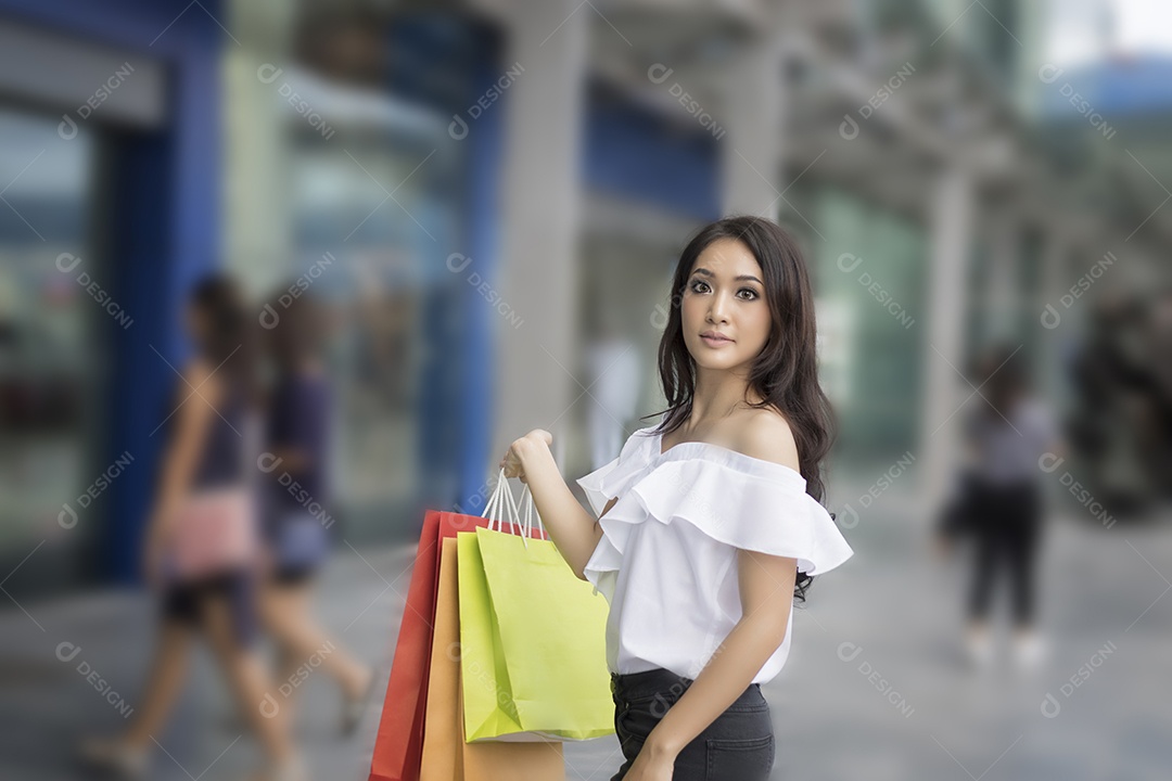 As mulheres asiáticas e a linda garota estão segurando sacolas de compras