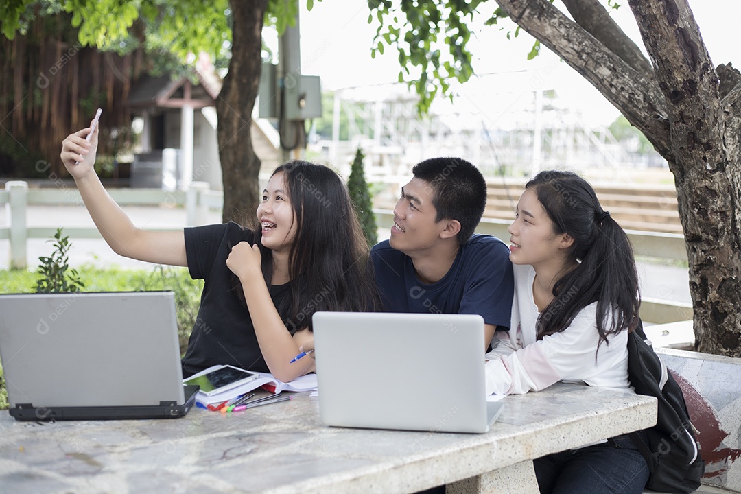 Grupo asiático de estudantes usando tablet e notebook compartilhando