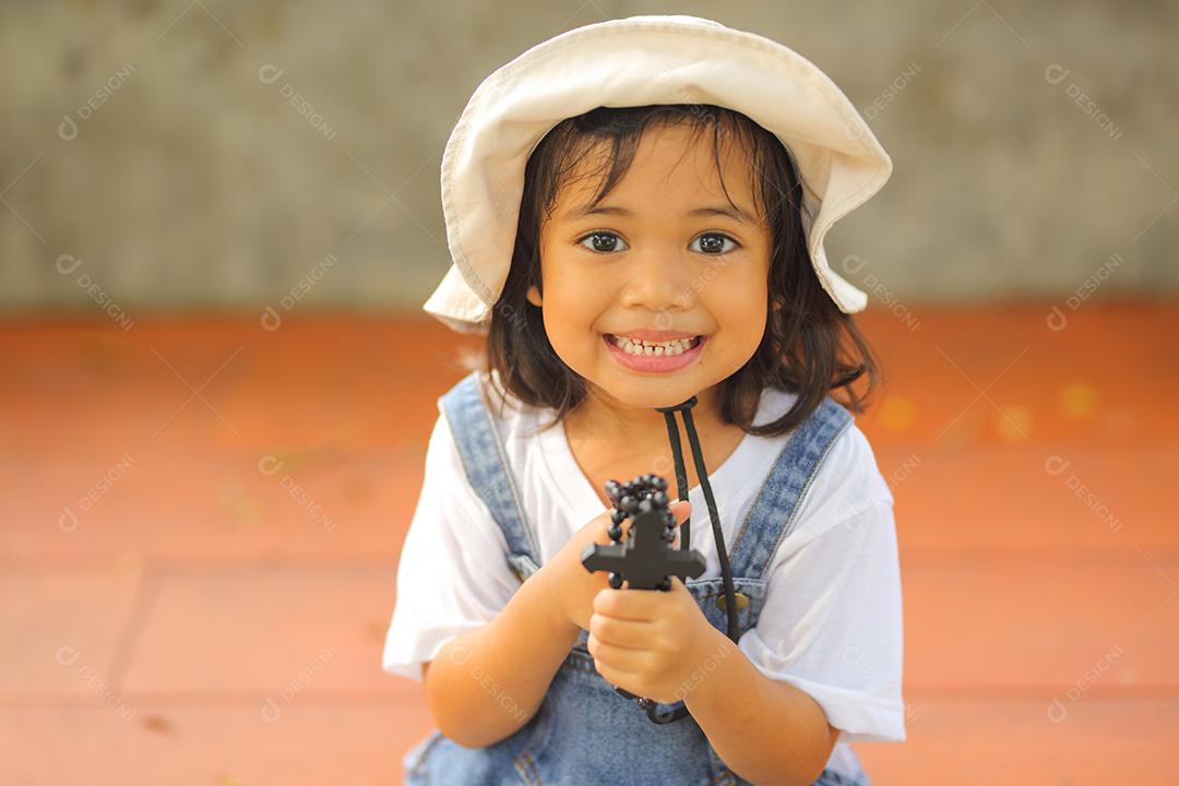 Menina asiática rezando a bênção de Deus e segurando a cruz de madeira