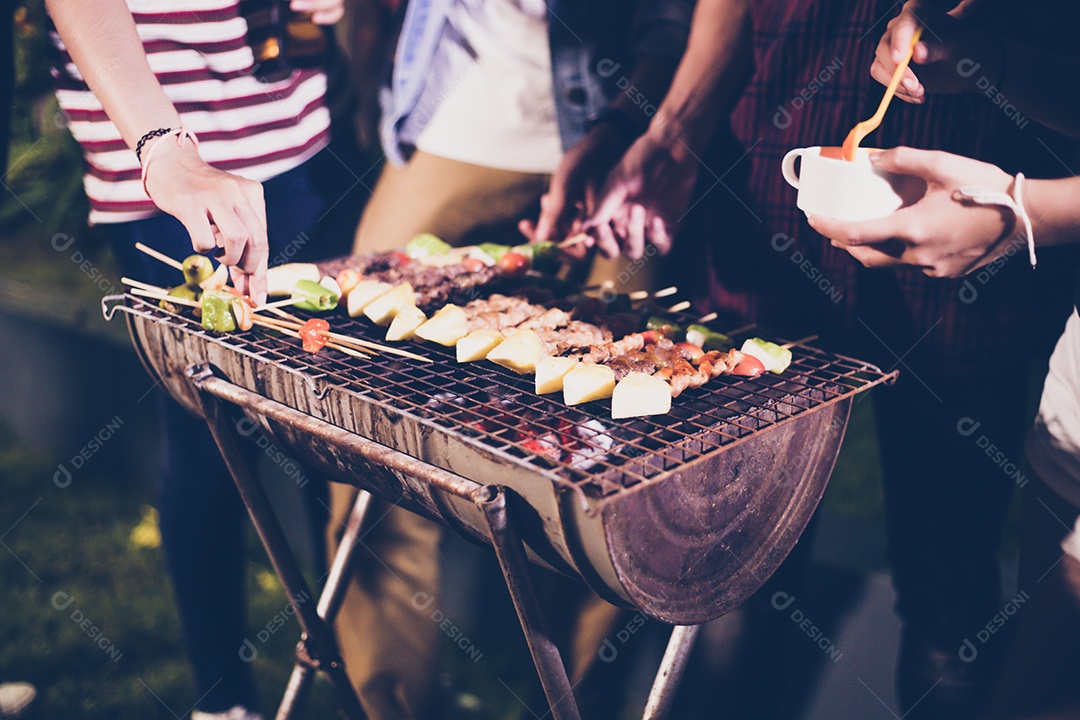 Grupo asiático de amigos fazendo churrasco no jardim ao ar livre rindo