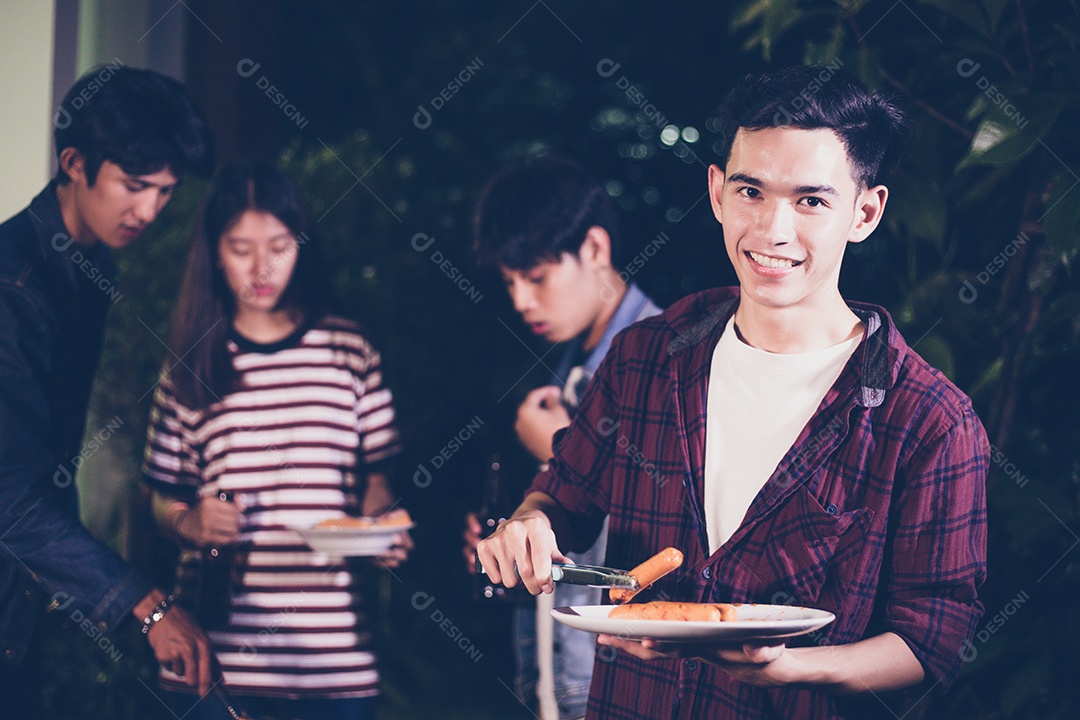 Grupo asiático de amigos fazendo churrasco no jardim ao ar livre rindo