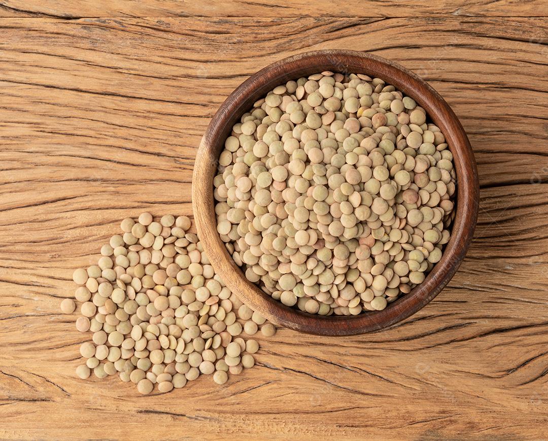 Lentilhas cruas em uma tigela sobre a mesa de madeira.