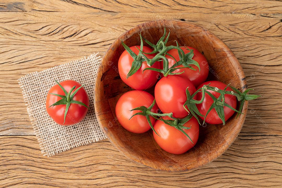 Tomates vermelhos em uma tigela sobre a mesa de madeira