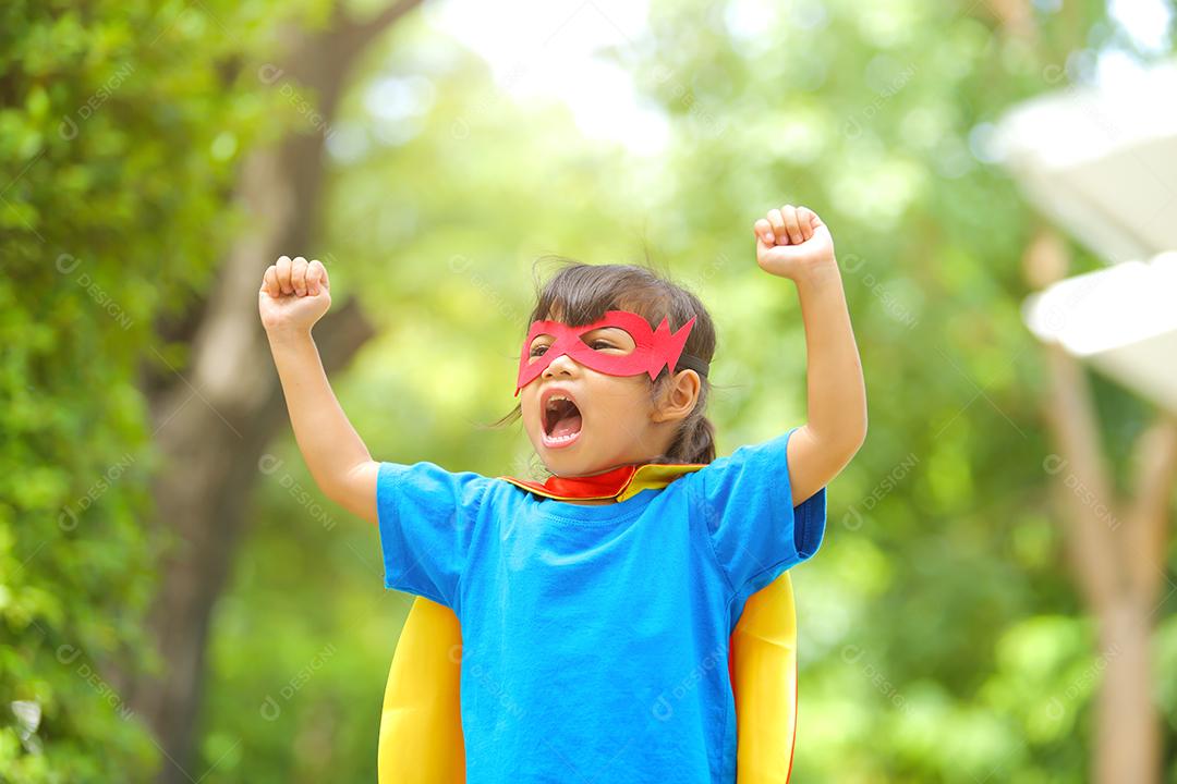 Uma menina bonitinha com máscara vestida e vestindo e capa de criança super-herói.