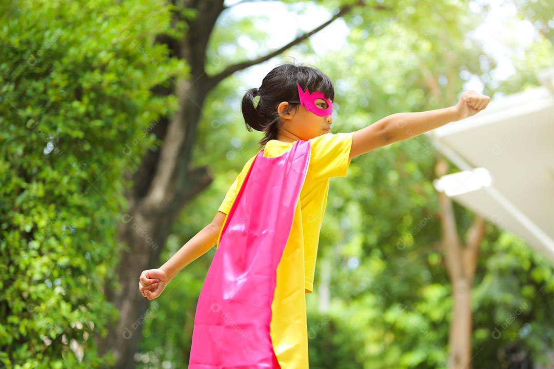 A cute little girl with dressed and wearing mask and superhero child cape.