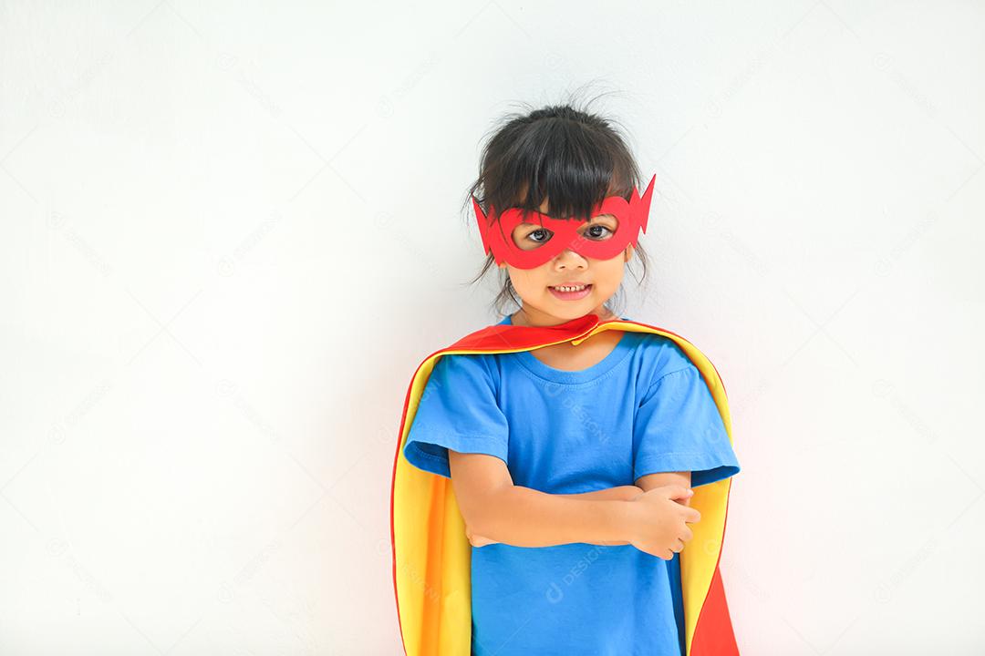 Uma menina bonitinha com máscara vestida e vestindo e capa de criança super-herói.