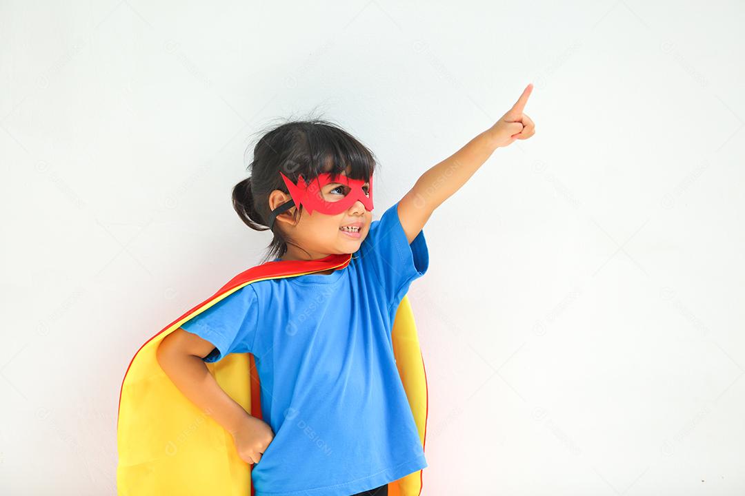 Uma menina bonitinha com máscara vestida e vestindo e capa de criança super-herói.