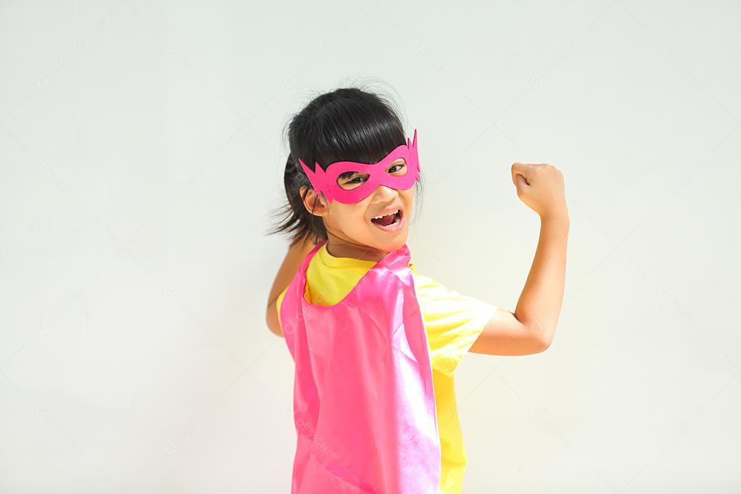 Uma menina bonitinha com máscara vestida e vestindo e capa de criança super-herói.