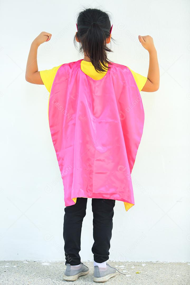 Uma menina bonitinha com máscara vestida e vestindo e capa de criança super-herói.