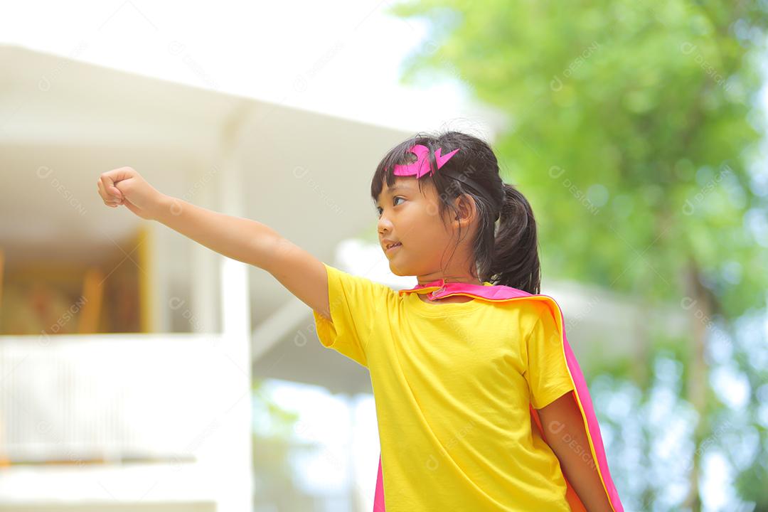 Uma menina bonitinha com máscara vestida e vestindo e capa de criança super-herói.