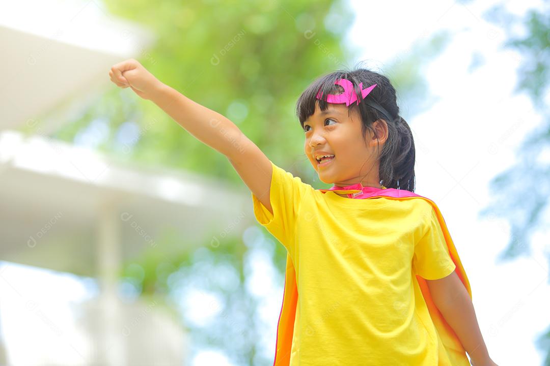 Uma menina bonitinha com máscara vestida e vestindo e capa de criança super-herói.