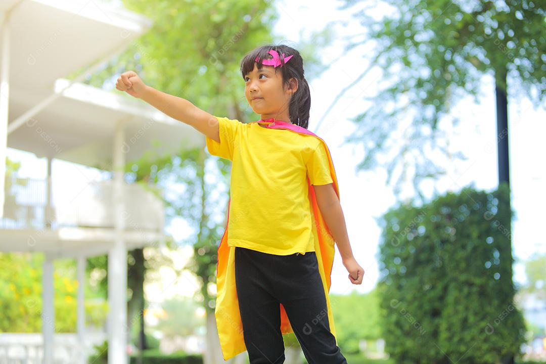 Uma menina bonitinha com máscara vestida e vestindo e capa de criança super-herói.