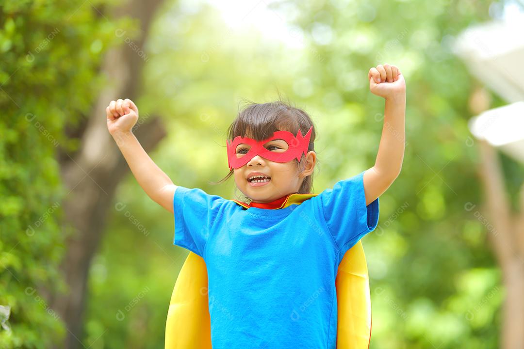 Uma menina bonitinha com máscara vestida e vestindo e capa de criança super-herói.