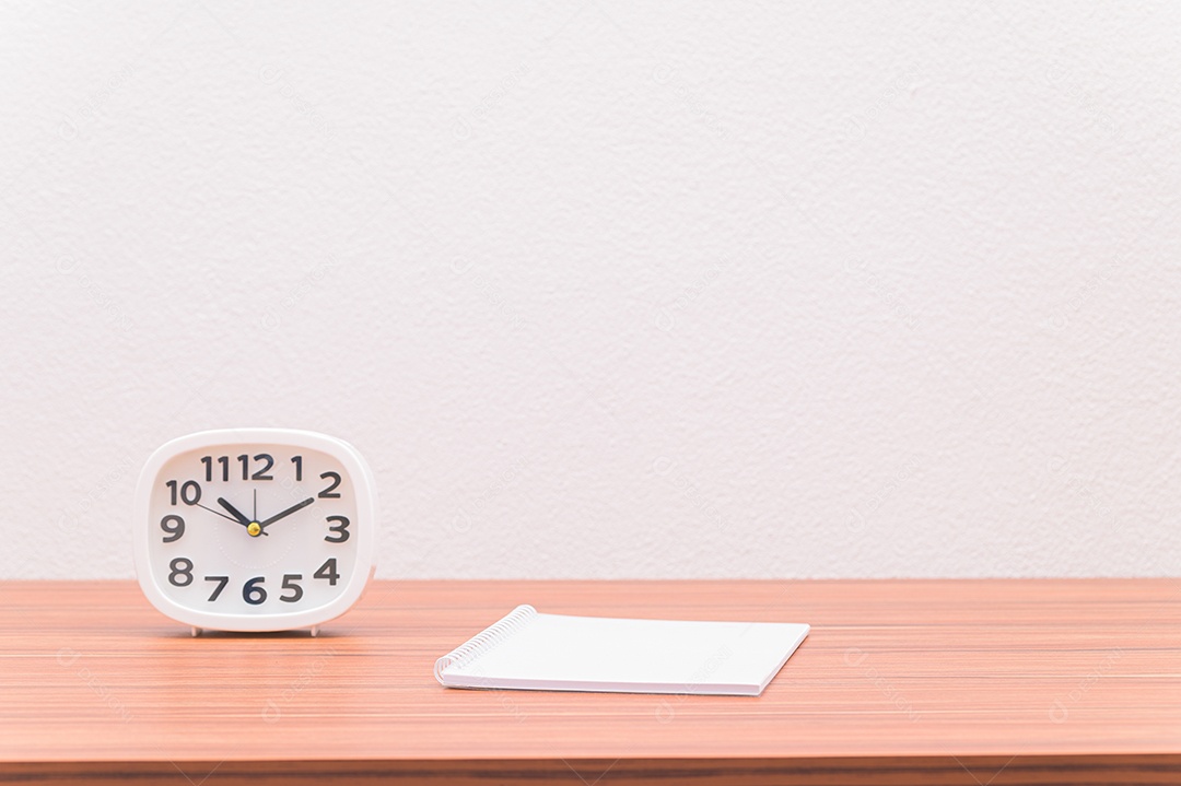 Caderno e o relógio estão sobre a mesa.