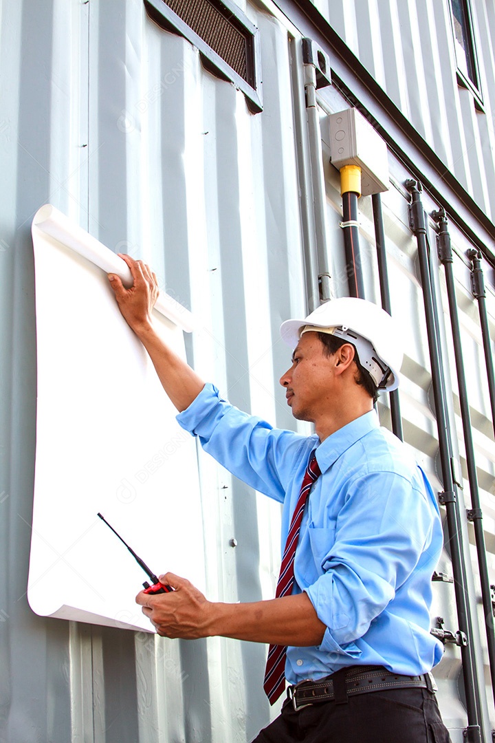 Jovem engenheiro civil segurando a planta enquanto desvia o olhar