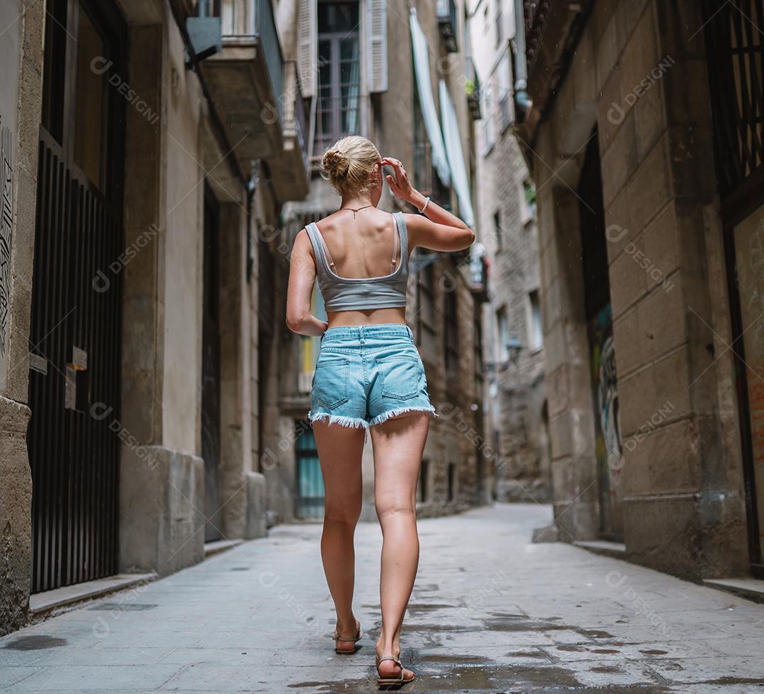 Feliz turista feminina para trás andando no beco da cidade velha.