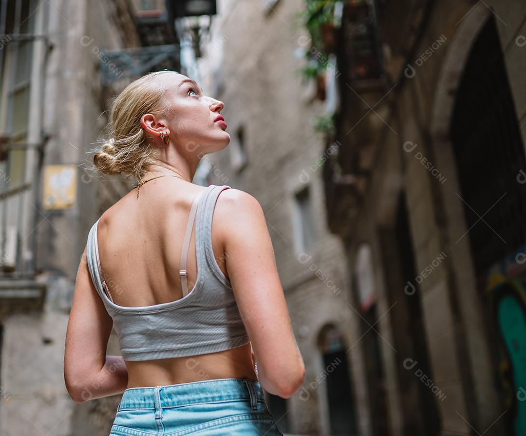 Feliz turista feminina para trás andando no beco da cidade velha.