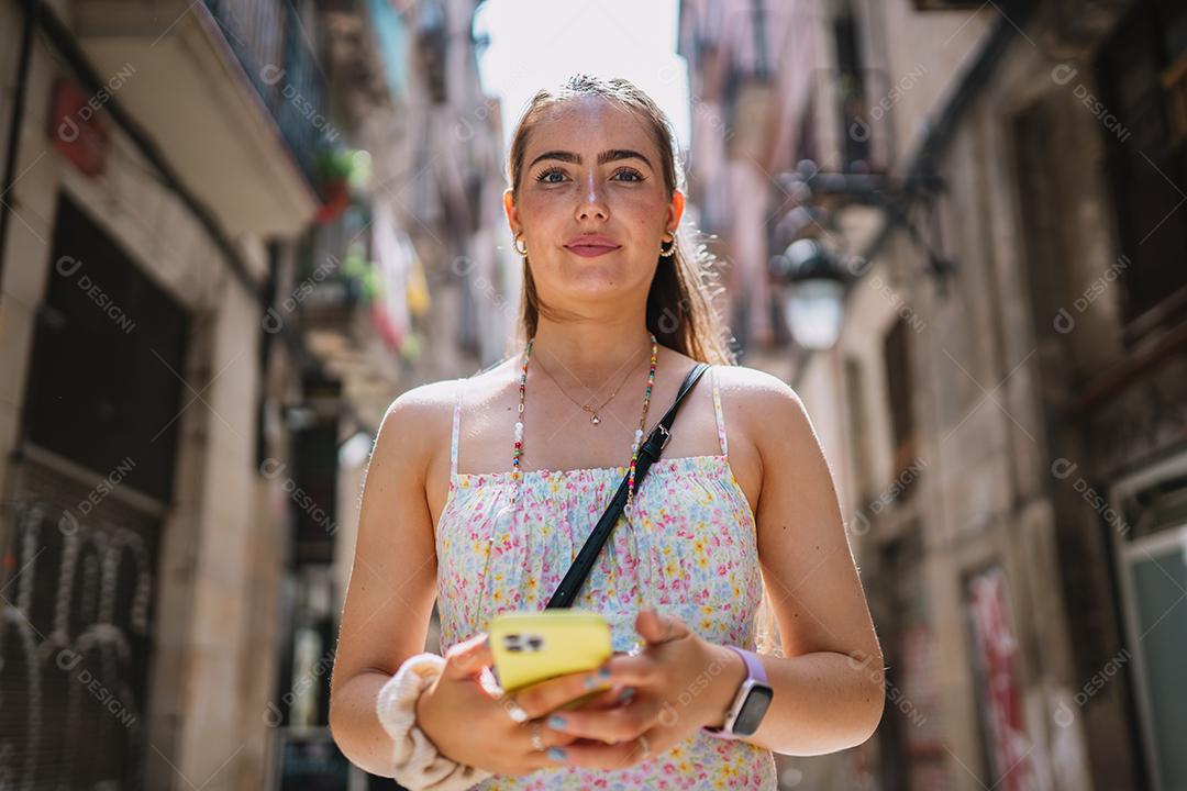 Feliz usuário de telefone turístico feminino andando no beco da cidade velha.