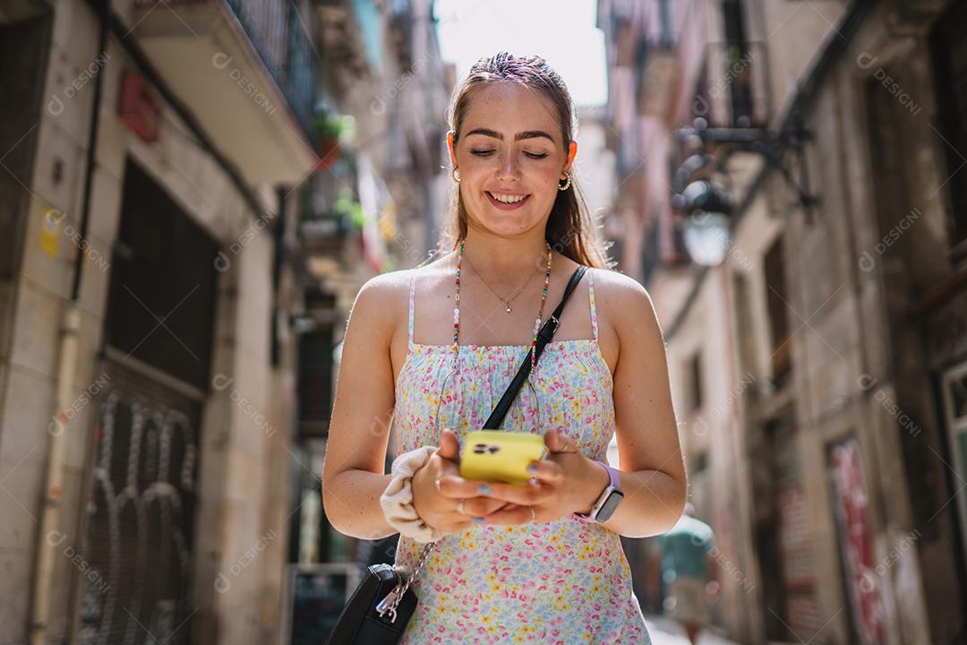 Feliz usuário de telefone turístico feminino andando no beco da cidade velha.