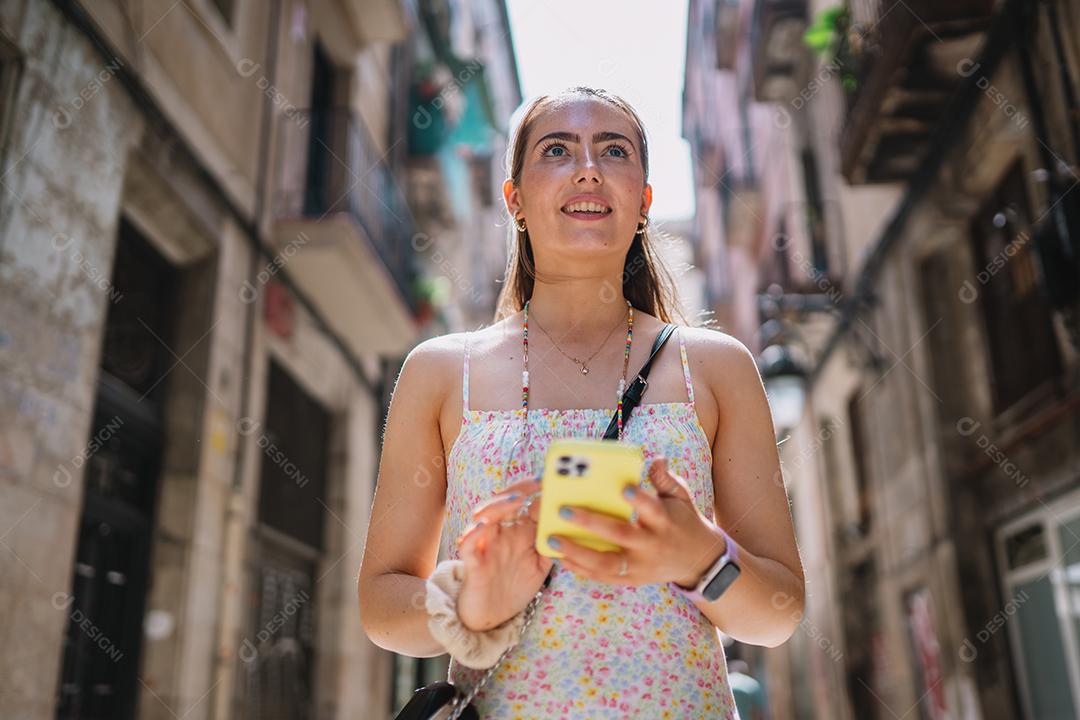 Feliz usuário de telefone turístico feminino andando no beco da cidade velha.