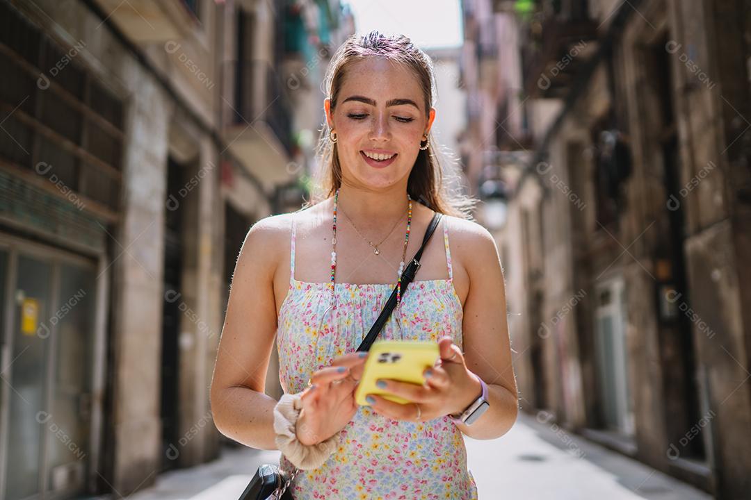 Feliz usuário de telefone turístico feminino andando no beco da cidade velha.