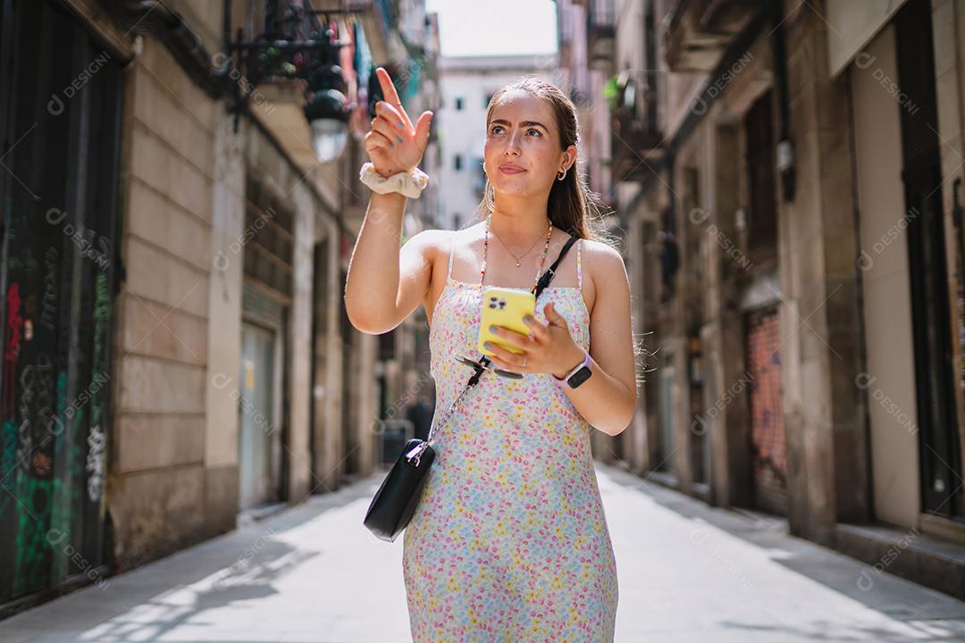 Feliz usuário de telefone turístico feminino andando no beco da cidade velha.