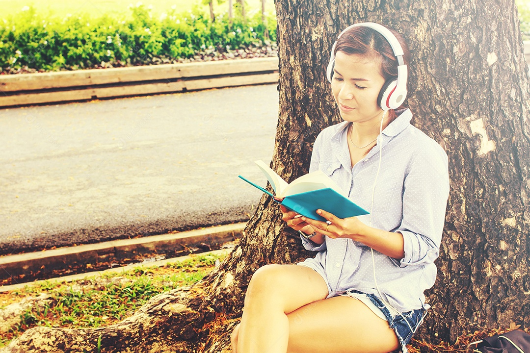 Jovem mulher com chapéu lendo um livro e curtindo um sol