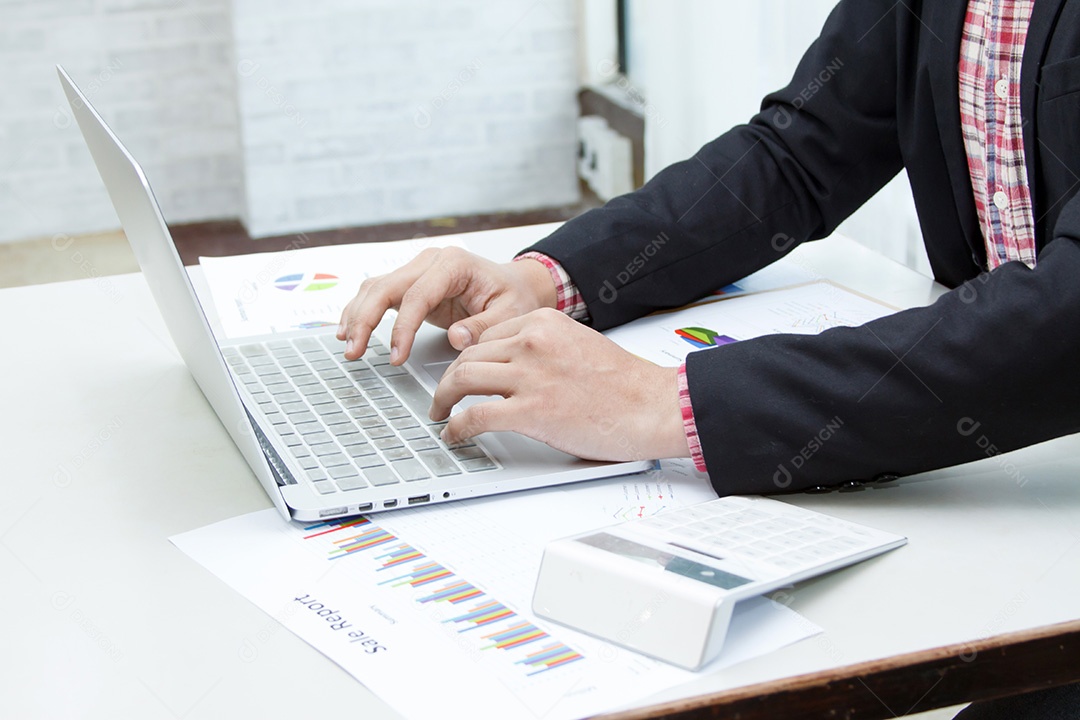 Empresário usando laptop na mesa coberta com gráfico financeiro