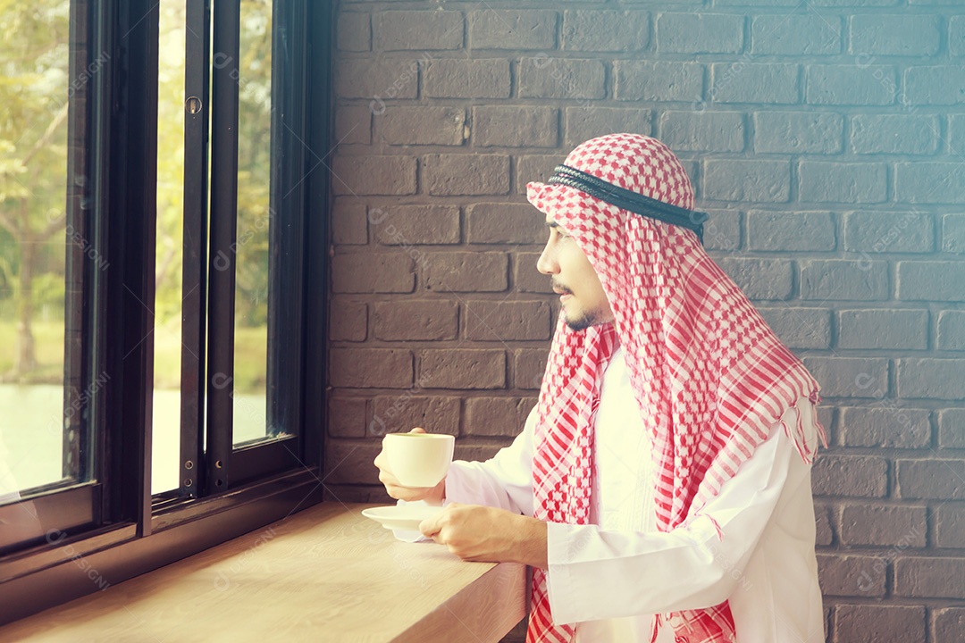 Homem saudita árabe bebe café na cafeteria e olha para as saídas