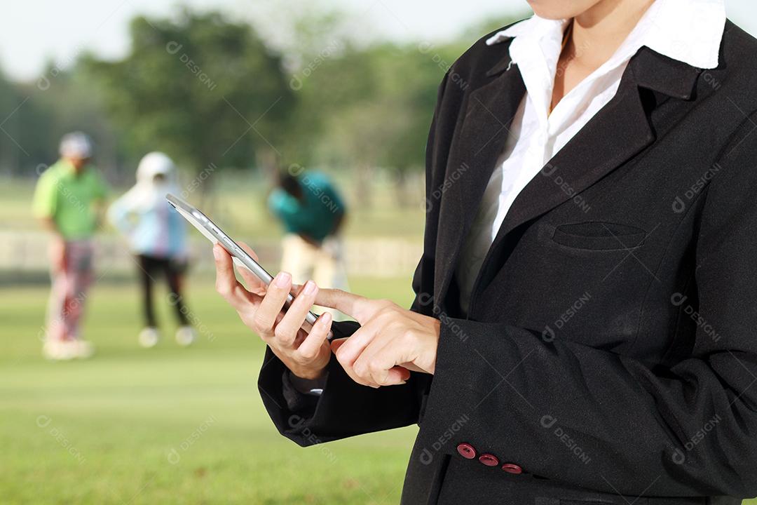 Empresário e mulher estão usando celular e telefone inteligente de toque em jogadores de golfe