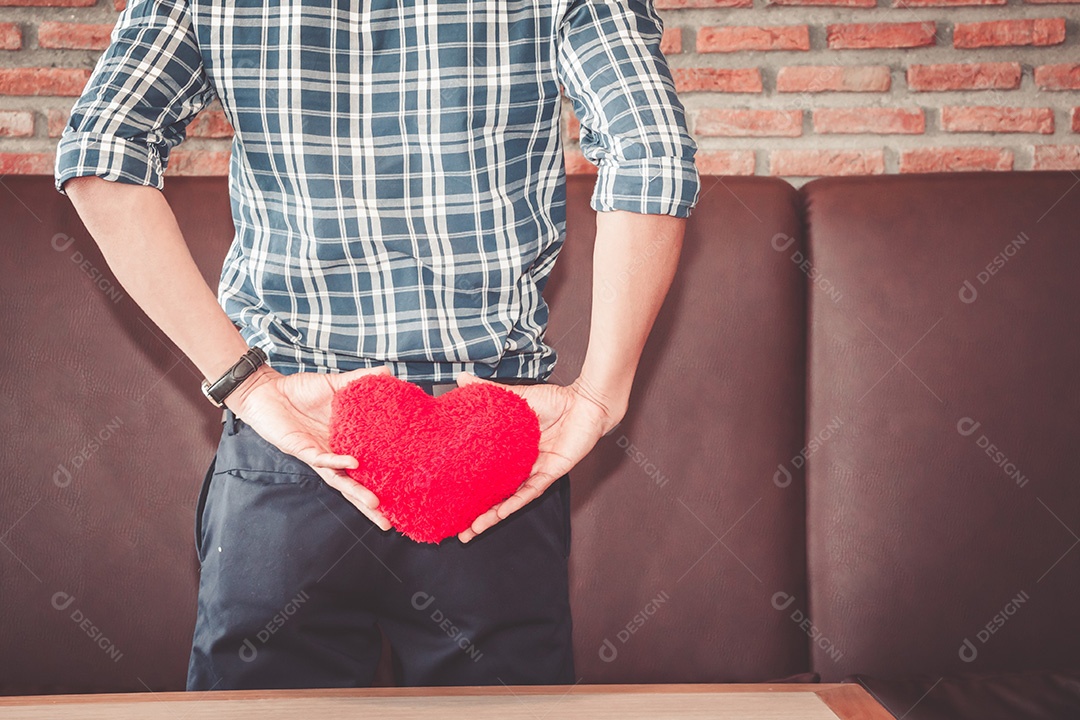Homem segurando coração vermelho em suas mãos vista traseira