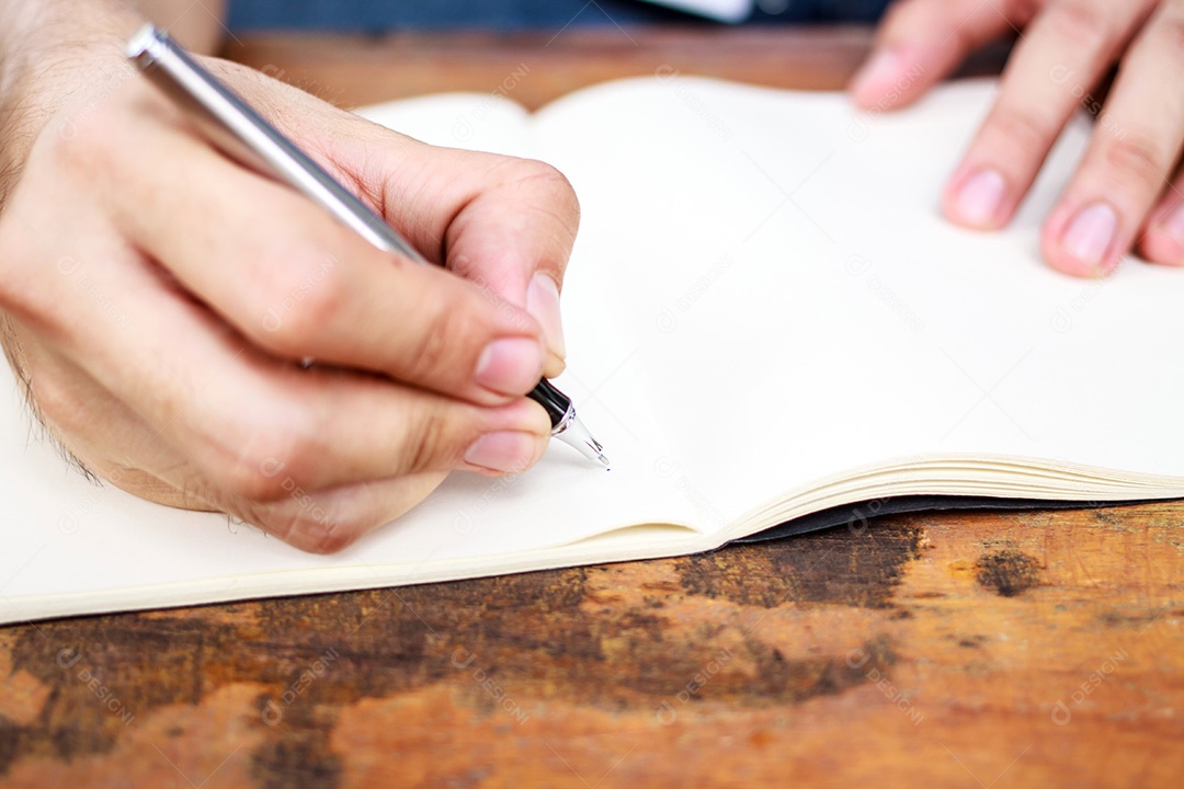Mãos com caneta escrevendo no caderno