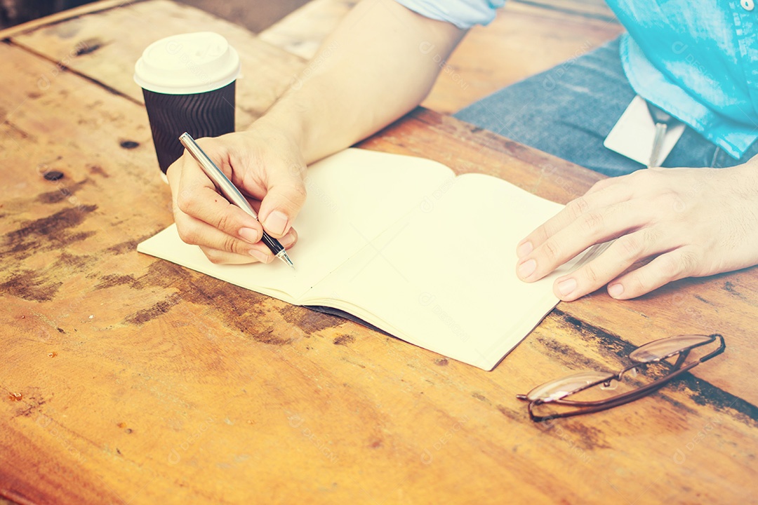 Fechar a mão masculina escrevendo no caderno sobre a mesa