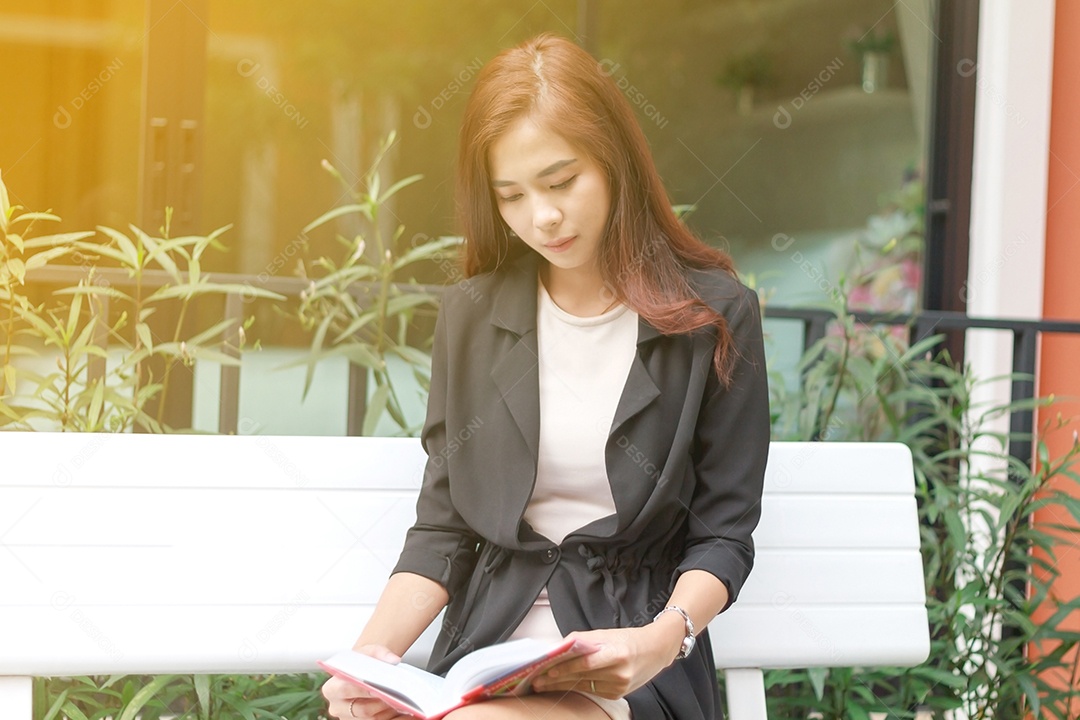Mulher asiática lendo um livro para relaxamento na luz solar  e embaçado
