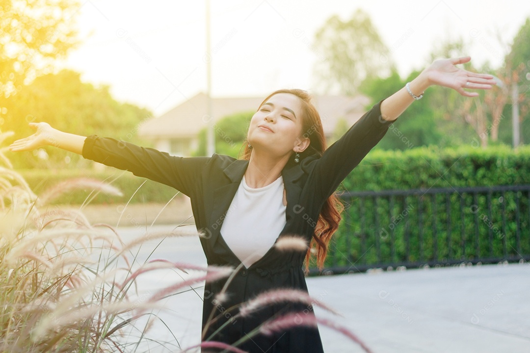 Mulher de negócios bem-sucedida com os braços para cima e feliz comemorando a mulher de sucesso ao pôr do sol