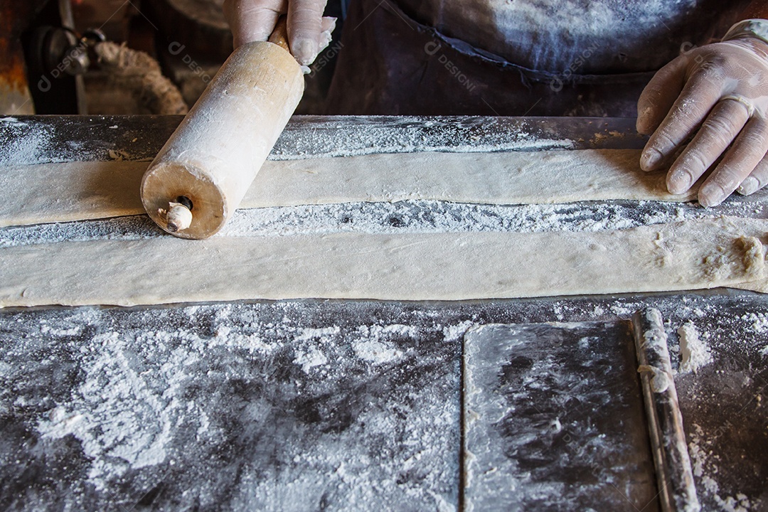 Cozinheira feminina rolando massa com rolo. Visão aproximada