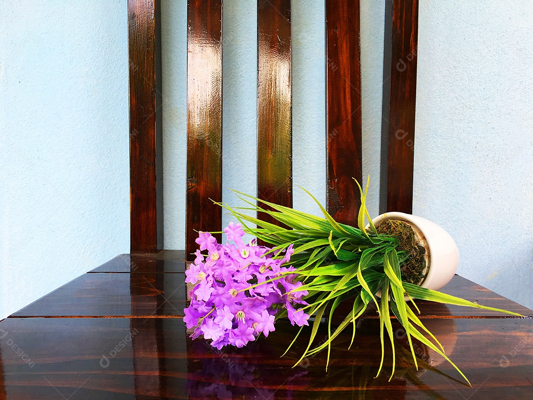 Vaso de flor caído sobre cadeira de madeira