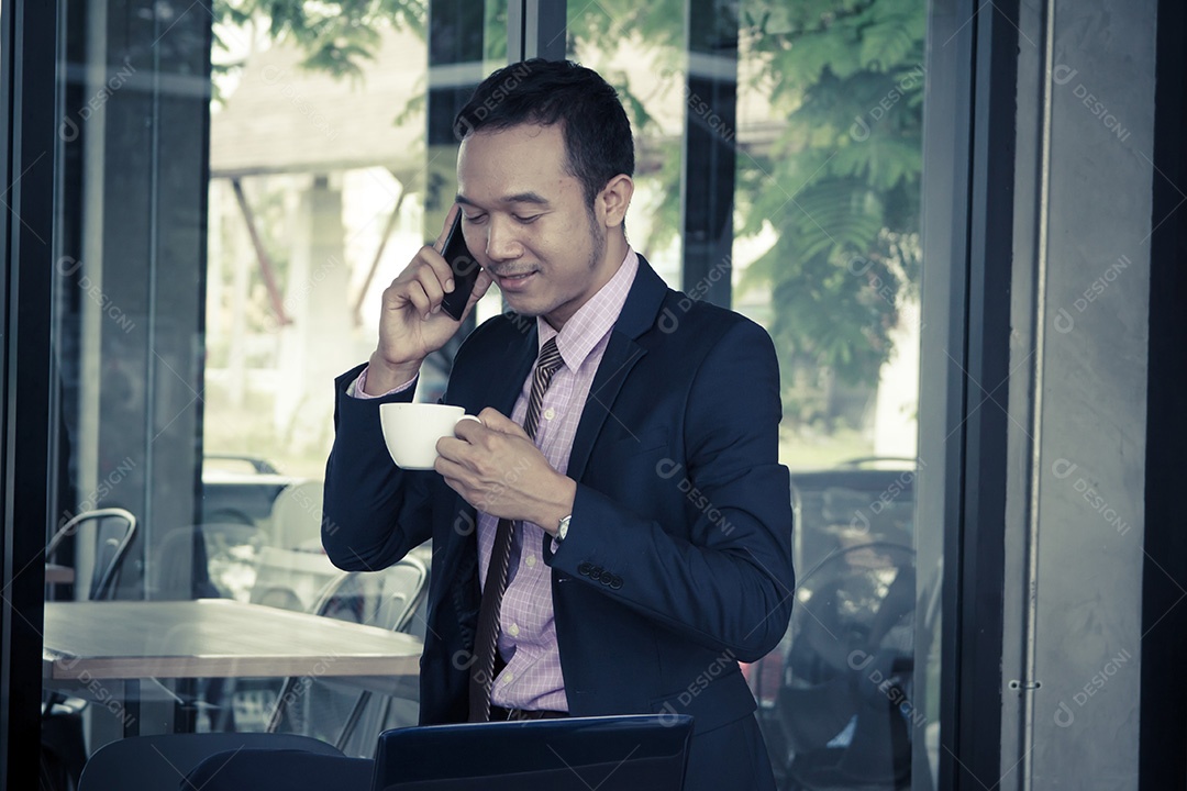 Feliz jovem empresário no café, falando no celular, bebendo café