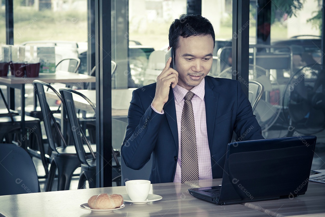 Feliz jovem empresário sentado no café, falando no celular