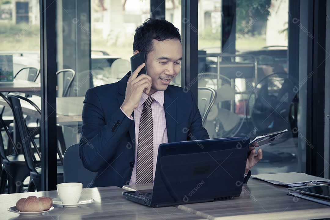 Feliz jovem empresário sentado no café, falando no celular