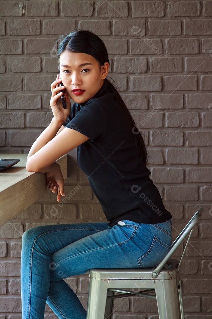 Mulher jovem e atraente com falar no telefonema no café.