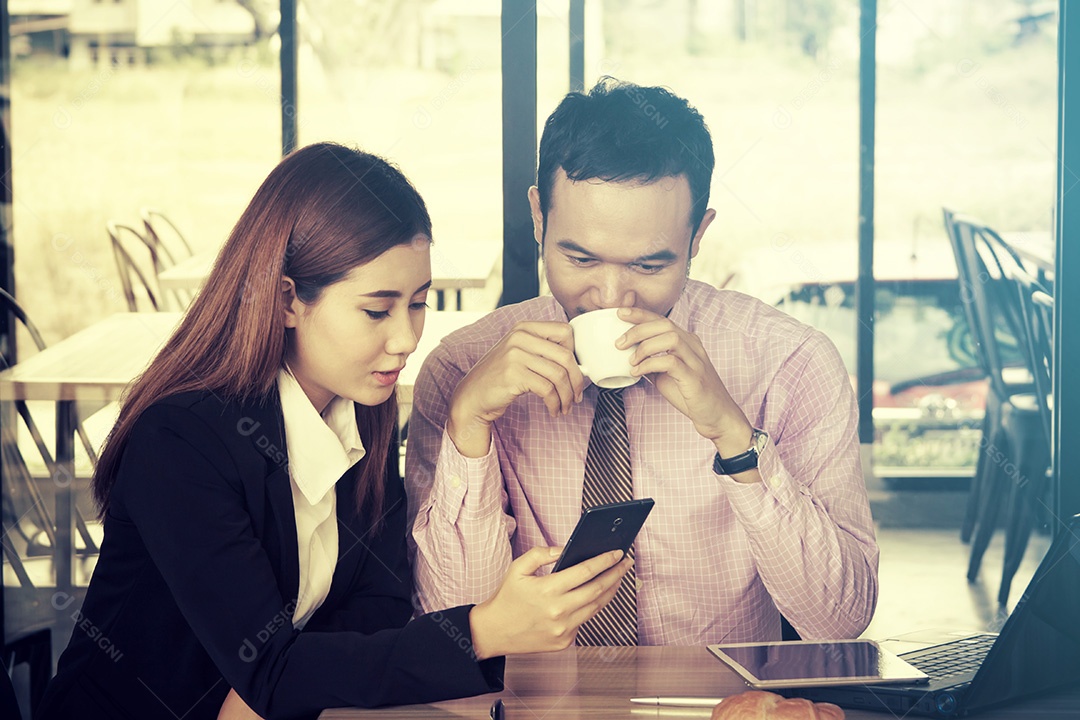 Feliz empresário e empresárias usando telefone inteligente no café