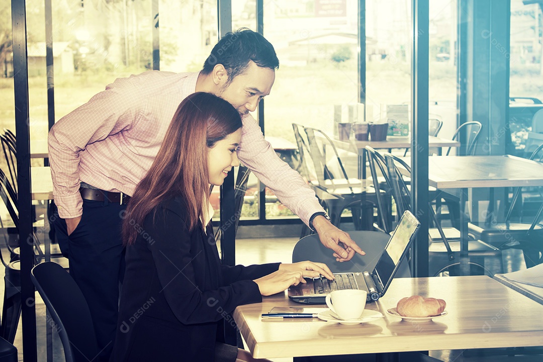 Jovem empresário e empresárias usando laptop em um café