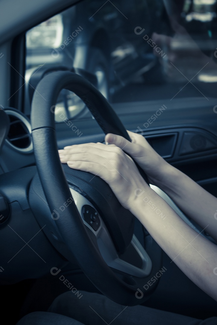As mãos da mulher apertam o botão no volante de um carro