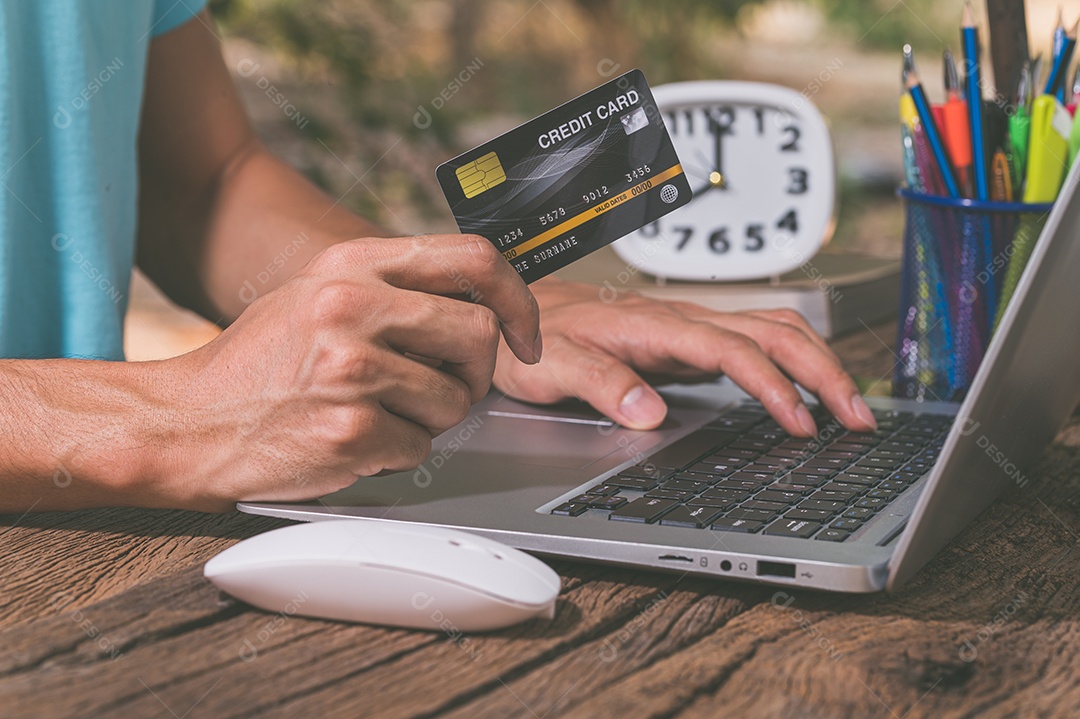 Pessoa usando cartões de crédito para fazer compras online por meio de notebook