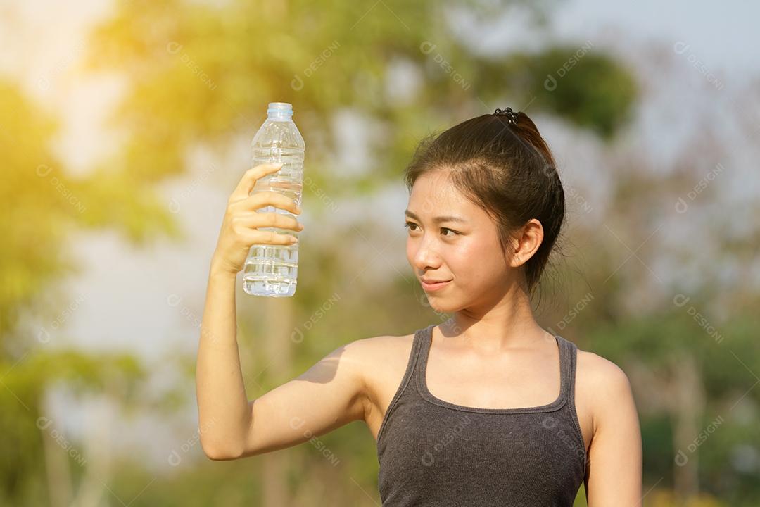 Mulher desportiva ásia bebendo água ao ar livre em dia ensolarado