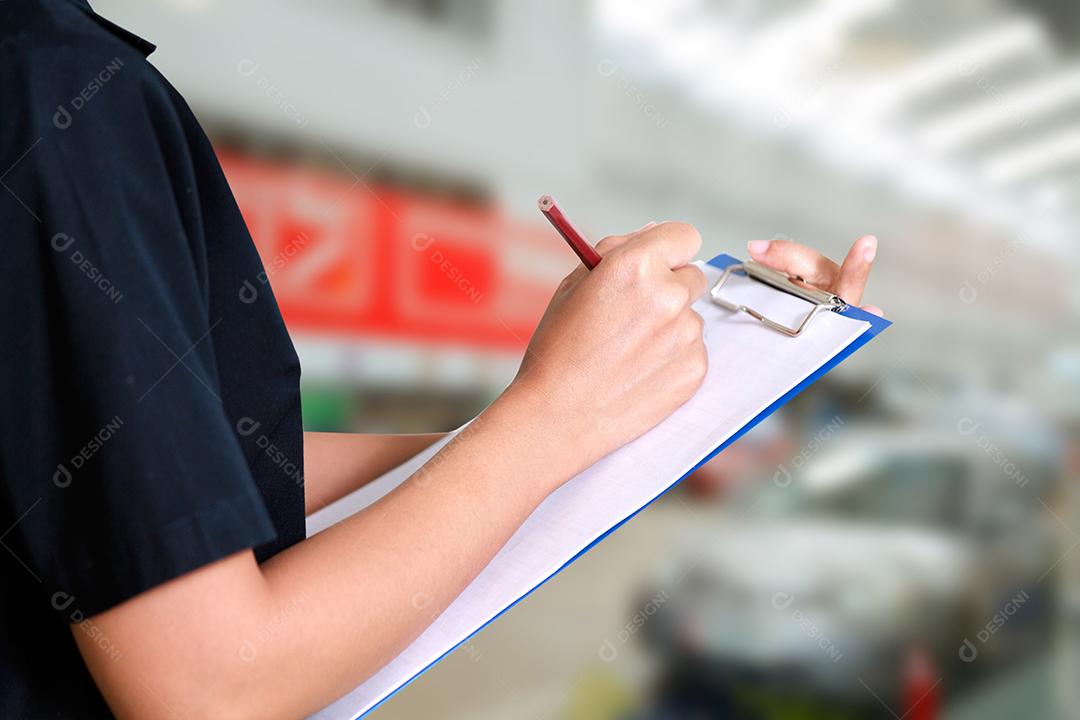 Retrato de uma jovem mecânica sorridente inspecionando um carro na oficina de automóveis