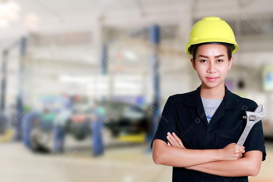 Engenheira asiática segurando uma chave na mão, preparada para os carros de reparo em elevadores