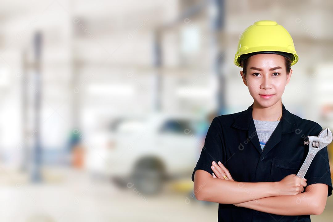 Engenheira asiática segurando uma chave na mão, preparada para os carros de reparo em elevadores